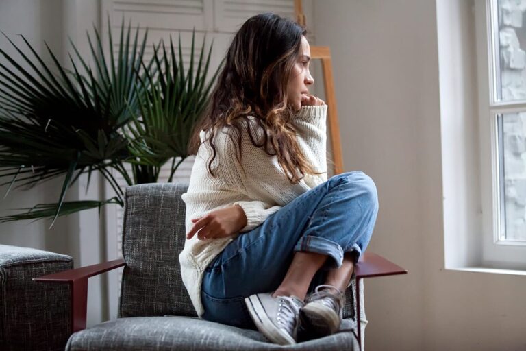 girl curls up on chair and considers anticipatory anxiety
