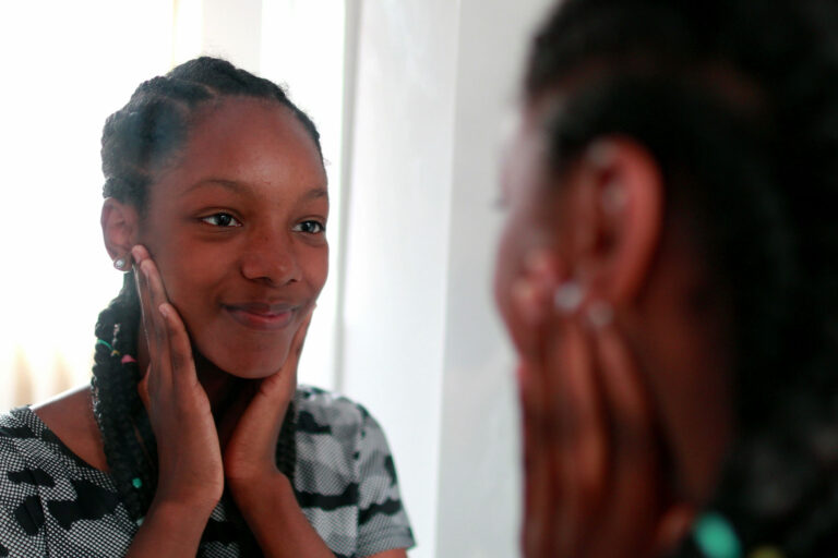 teen girl looks in the mirror and thinks about hygiene indifference