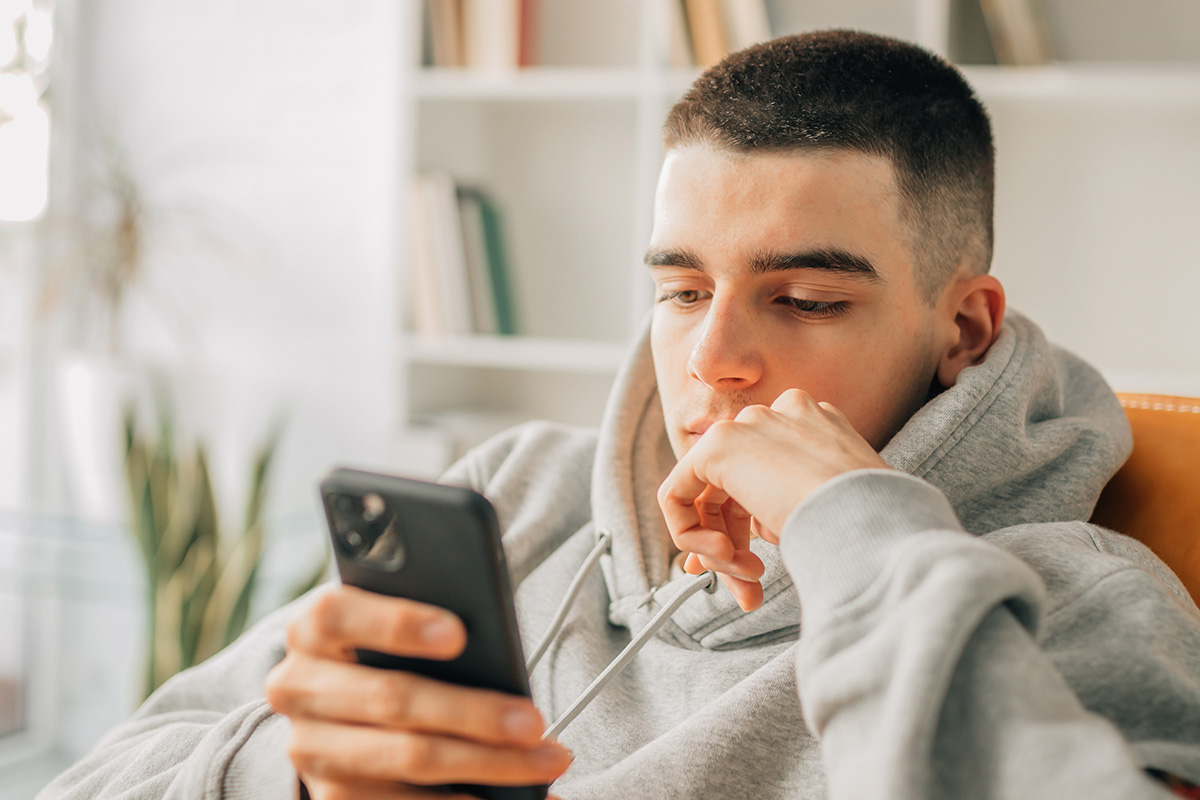 teen looking at his phone and thinking about mental health